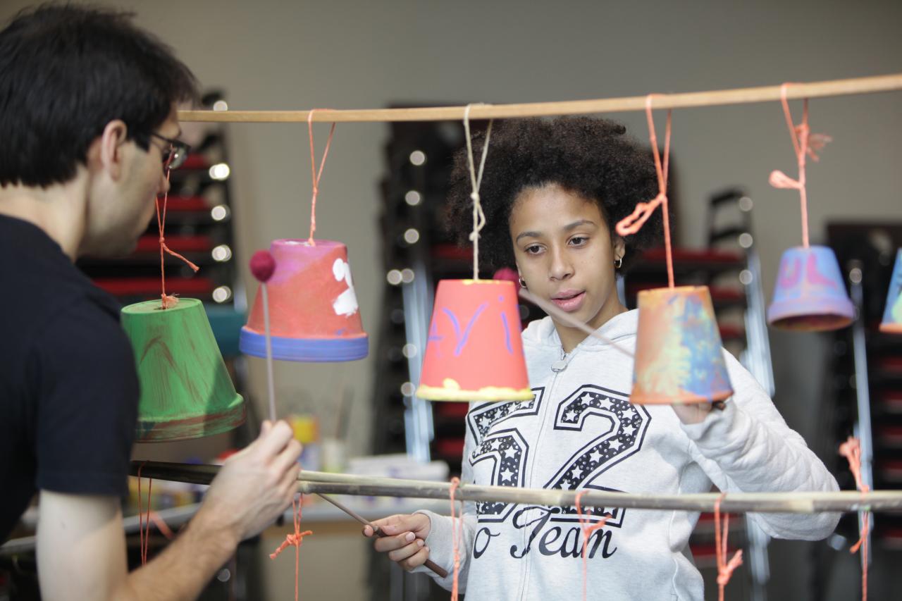 Une enfant jouant d'un instrument fabriqué en carton