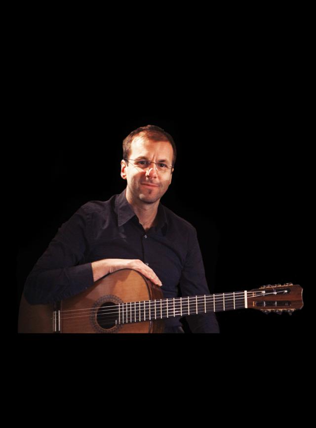 A smiling man with a guitar in his hand