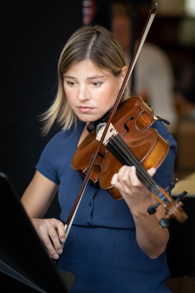 A woman sitting in front of a music stand playing a violin