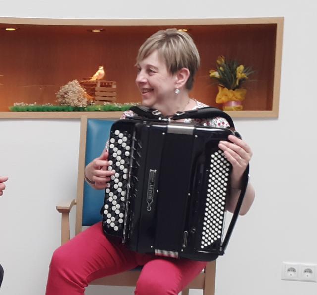 A woman sits on a chair and plays the accordion