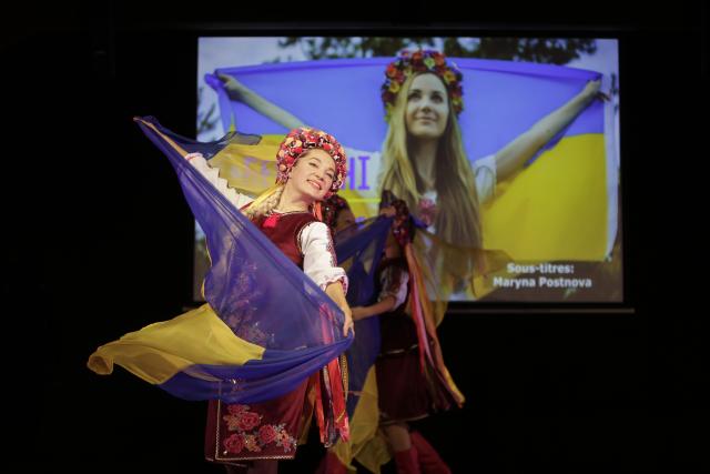 Une femme en habit traditionnel ukrainien dansant avec le drapeau ukrainien