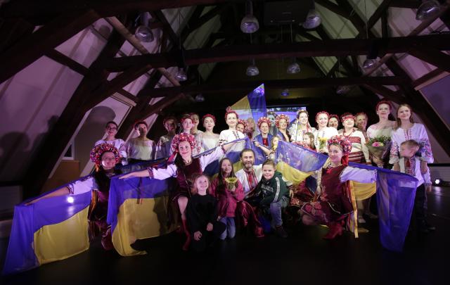 Un groupe de danse en habits traditionnels ukrainiens posant pour la photo avec des drapeaux ukrainiens