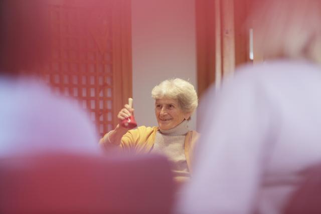 Une personnne âgées secouant une clochette en souriant