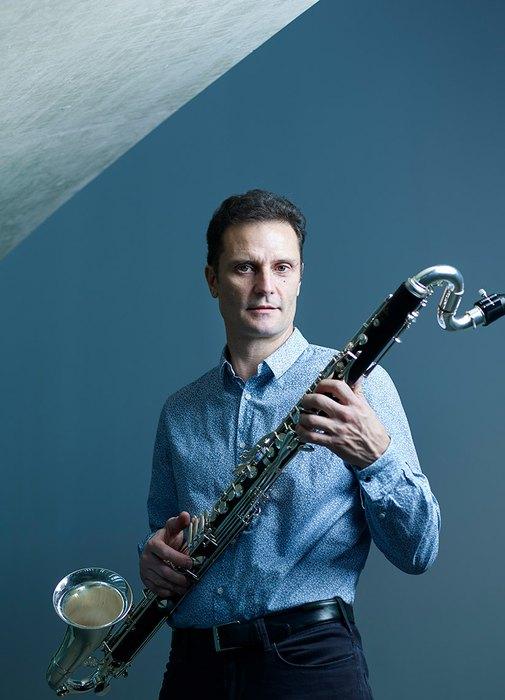 A standing man with a bass clarinet in his hand