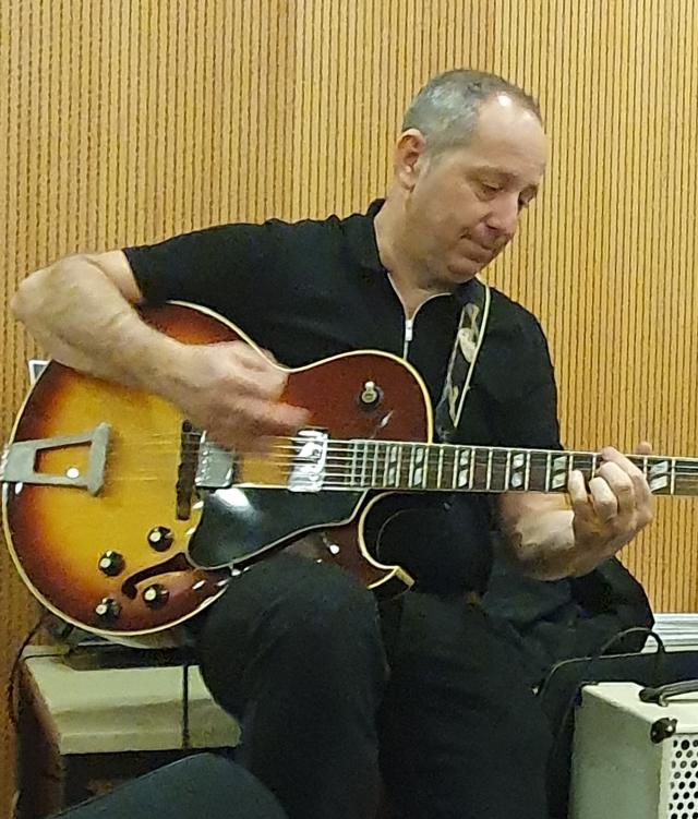 A man sits and plays the guitar