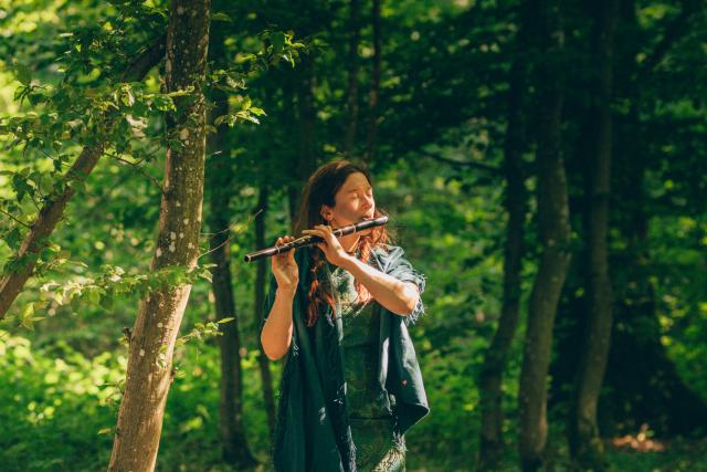 Une femme jouant de la flûte traversière dans un bois