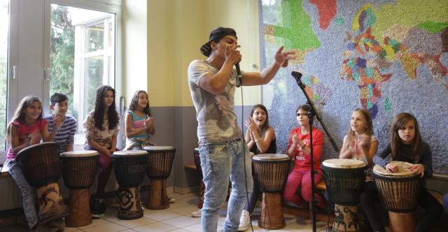 Des enfants jouant du djembé et un chanteur au milieu