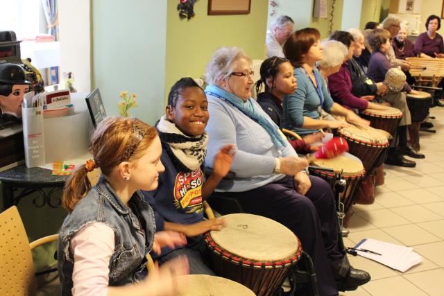 Des jeunes et personnes âgées jouant du djembé ensemble