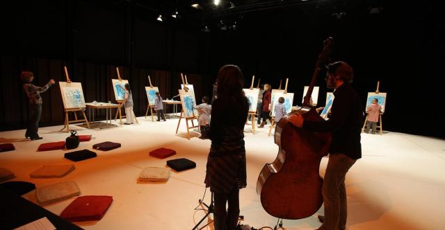 Des musiciens jouant au milieu de personnes peignant des tableaux