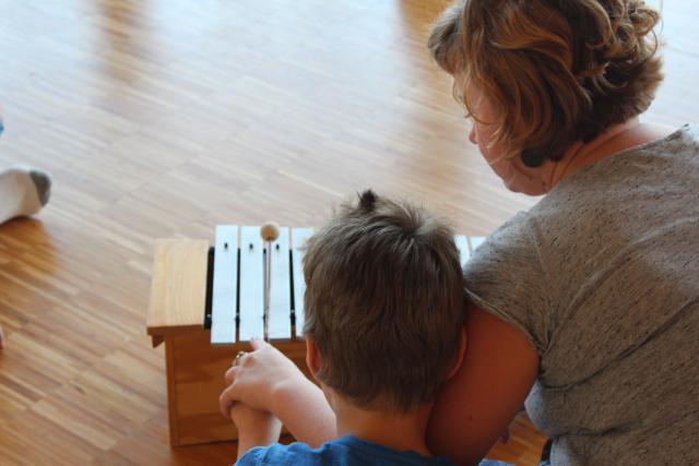 Une femme aidant un enfant un jouer du xylophone