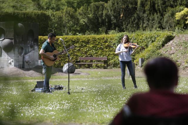 Un homme jouant de la guitare et une femme du violon dans un jardin