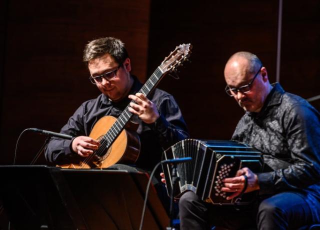 2 Männer im Halbdunkel, die Bandoneon und Gitarre spielen