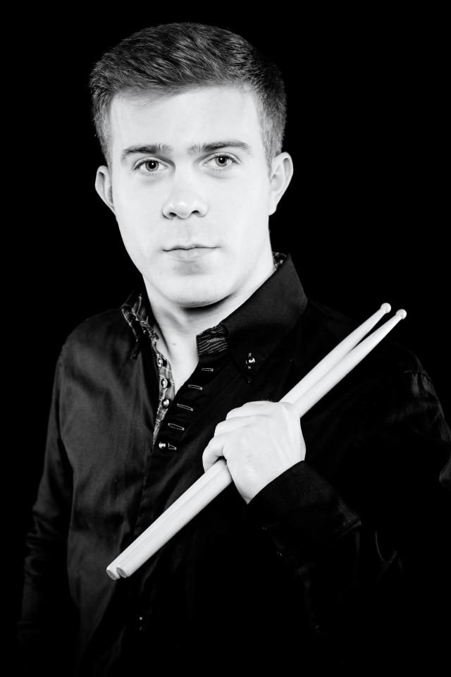 A man in front in black and white with drumsticks in his hand